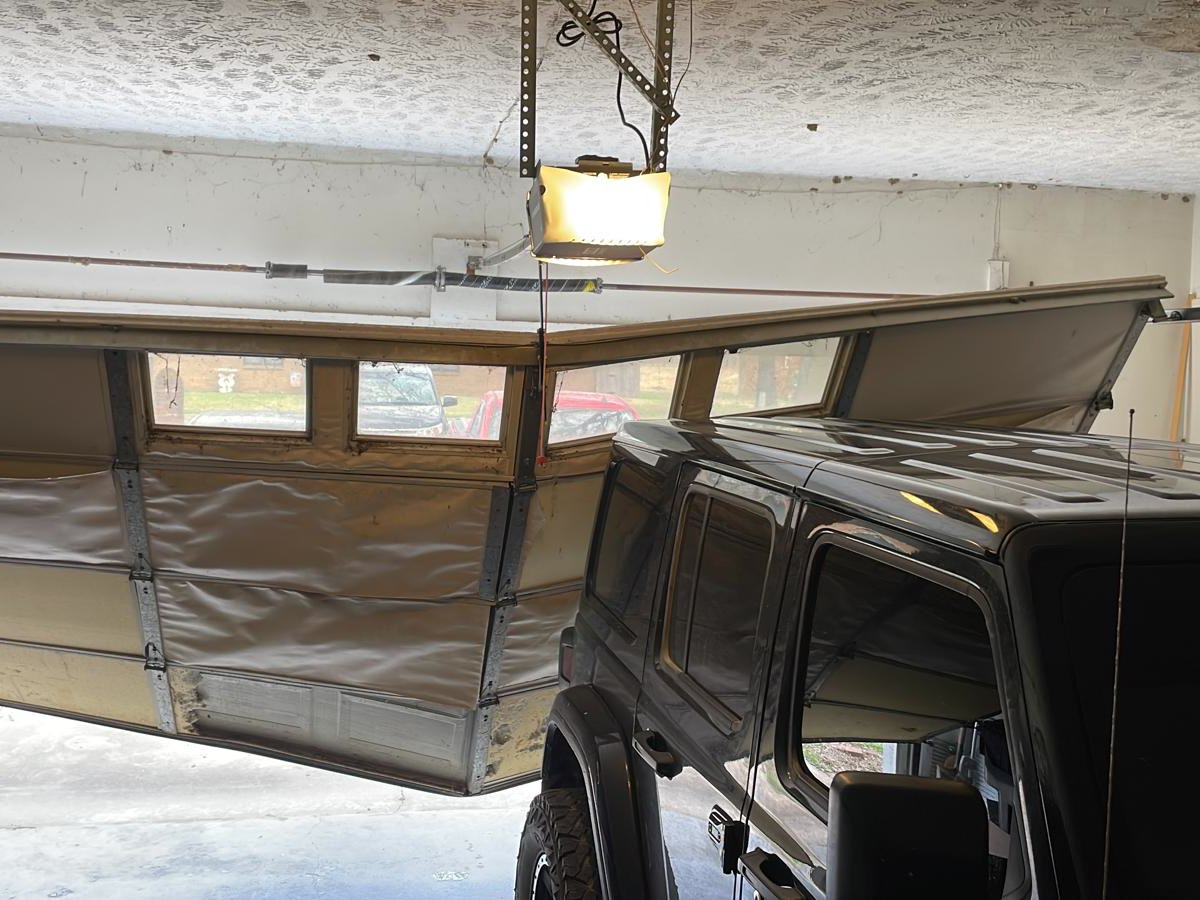 Buckled garage door with bent panels before repair in Tulsa