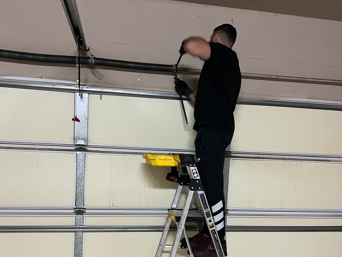 Infinity Garage Door Repair technician working on the shaft above a Tulsa garage door